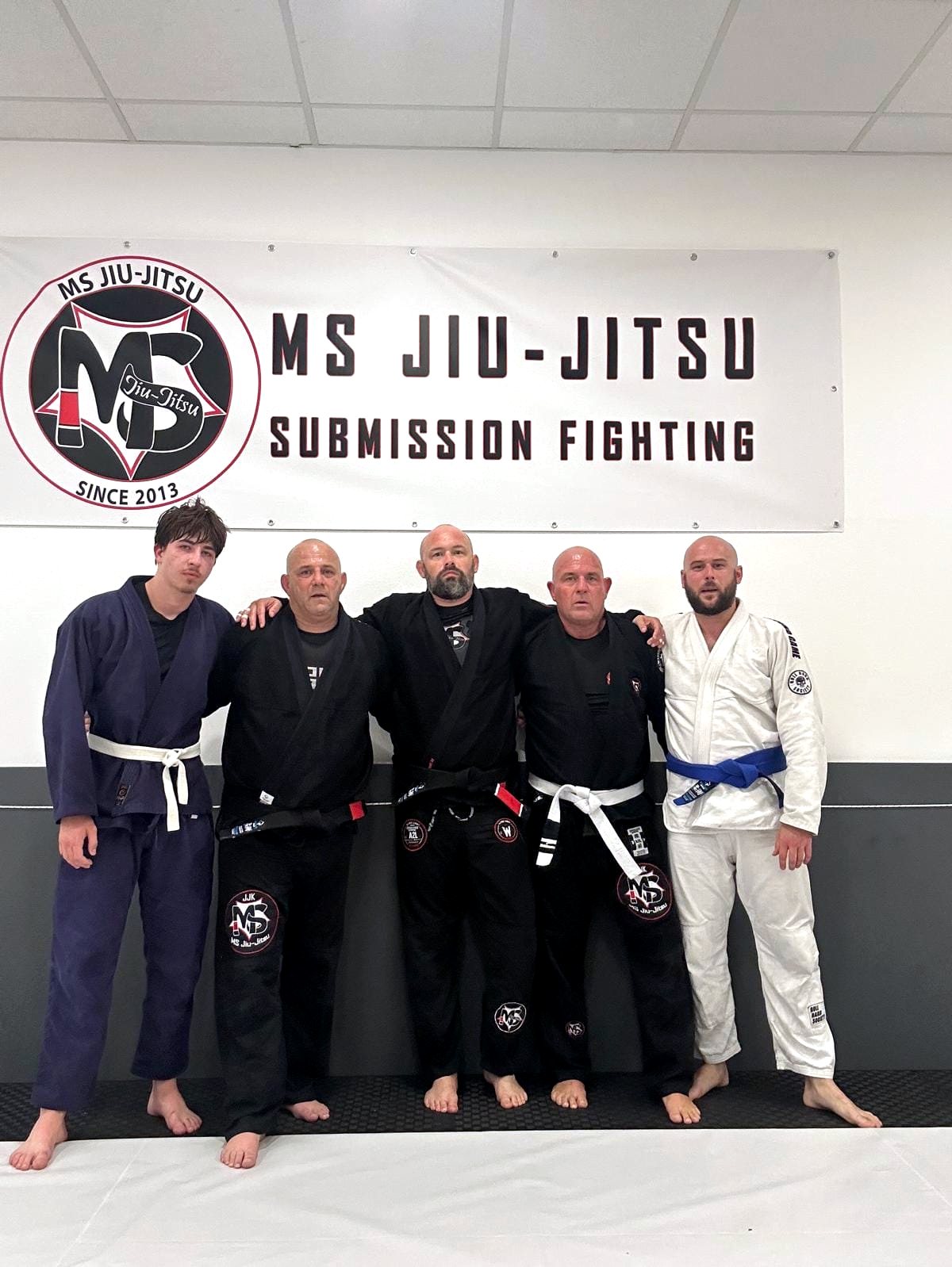 Trainingsgruppe von MS Jiu-Jitsu vor dem Banner in der Trainingshalle
